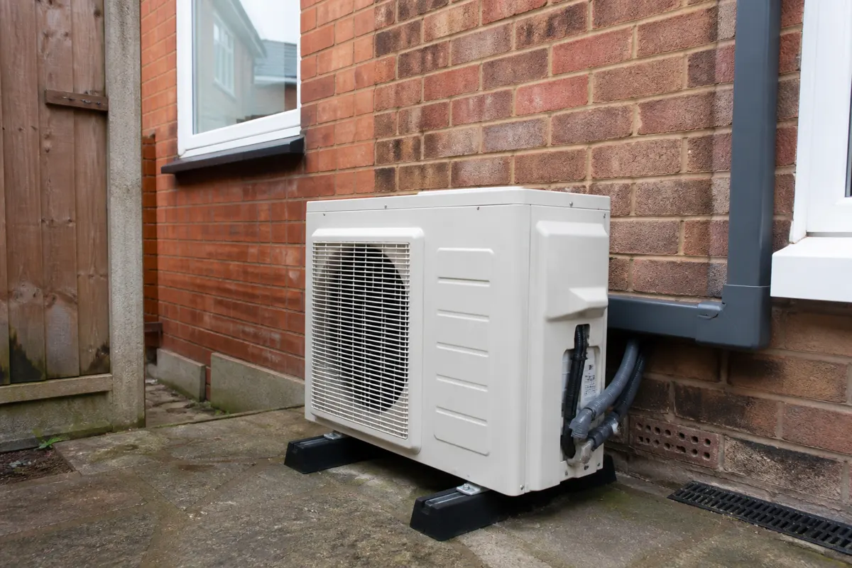 Outdoor condenser with several insulated refrigerant pipes on a UK house side wall