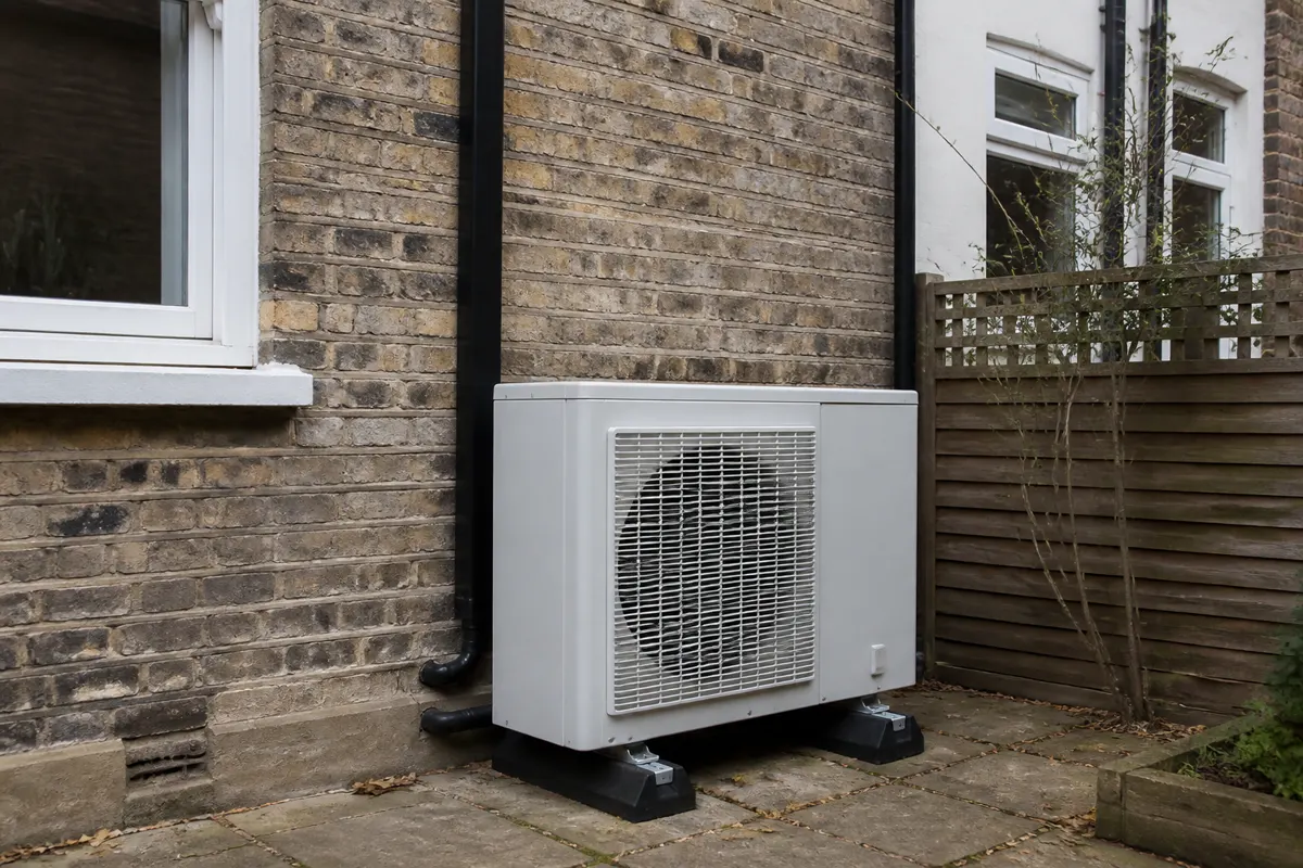 Large outdoor air conditioning condenser on a brick terrace rear wall in the UK