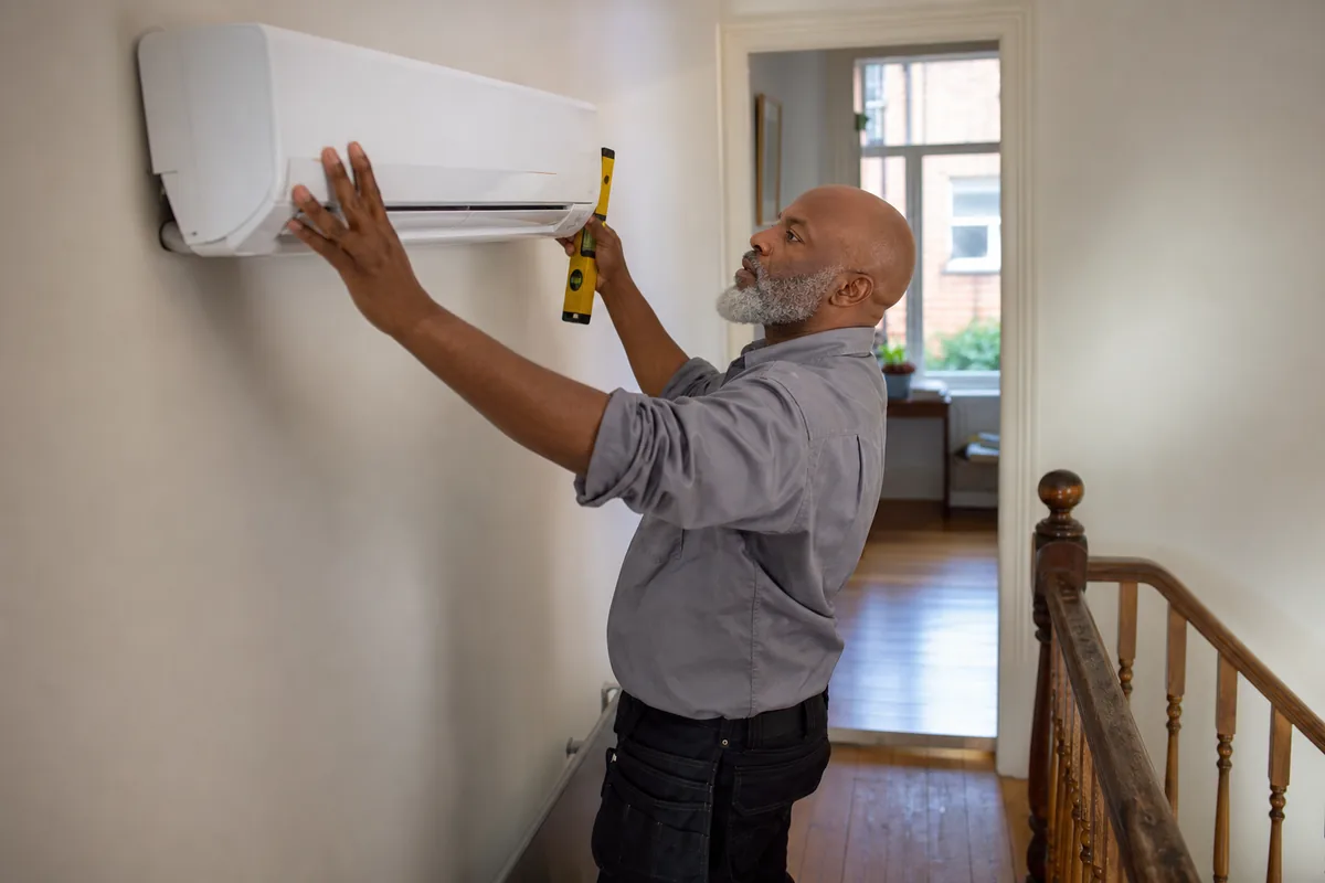 Air conditioning engineer fitting a wall-mounted indoor unit in a London home
